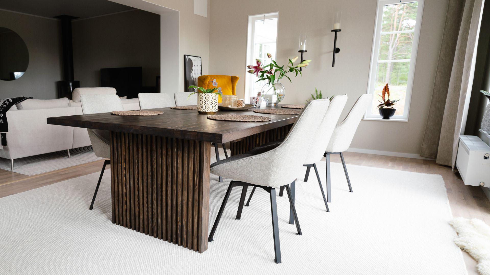 Rektangulært spisebord med rette sider med ribber. Spisebordet er brunt og har beige stoler rundt.